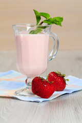 Glass of yogurt  with mint and fresh strawberries on the table