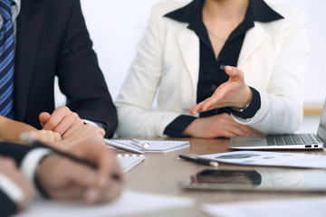 Group of businesspeople or lawyers discussing contract papers and financial figures while sitting at the table. Close-up of human hands at meeting or negotiations. Success and communication concept