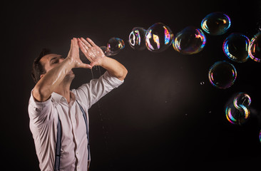 Artist blowing many soap bubbles from his hands. Bubble show studio concept.