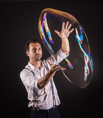 Artist hold big soap bubble in his hands. Bubble show studio concept.