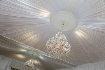 grand lustre avec pampilles et plafond blanc en tissu dans salle cérémonie mariage 