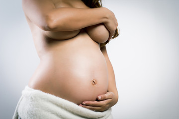 Beautiful pregnant latin woman on a gray background
