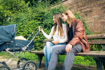 Fototapeta premium Young Parents With Baby Stroller In The Park
