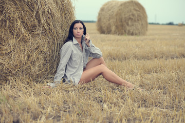woman sitting in field with haystacks