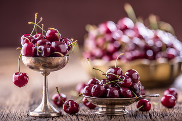 Cherries. Fresh sweet cherries. Delicious cherries with water drops in retro bowl on old oak table.