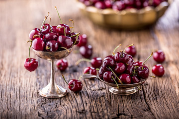 Cherries. Fresh sweet cherries. Delicious cherries with water drops in retro bowl on old oak table.