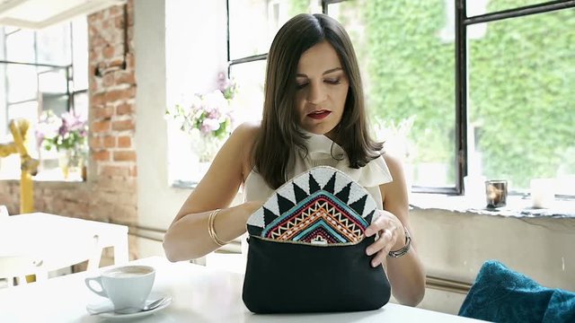 Elegant woman taking blush from her bag and applying on cheeks, steadycam shot
