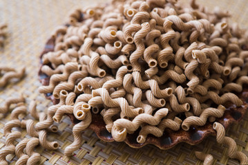 Pasta made from oat flour, scattered on a plate, on a table.