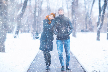 young man and woman in the snow in a city park couple winter