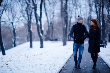 Fototapeta na wymiar young man and woman in the snow in a city park couple winter