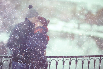 young man and woman in the snow in a city park couple winter