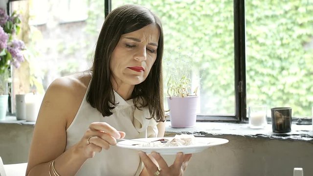 Elegant woman having indigestion while eating dessert in the cafe, steadycam shot
