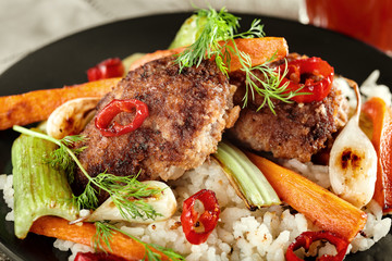 Cutlets with a garnish of rice and fried vegetables. Close-up, selective focus, toned in Photoshop.