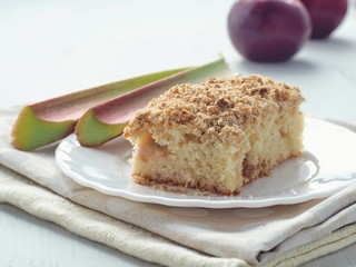Crumble cake decorated with fresh rhubarb stems and red apples. Homemade pudding. Selective focus.