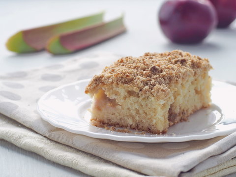 Coffee cake decorated with streusel and fresh rhubarb stems. Homemade apple pudding. Selective focus.