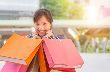 Close-up of young woman carrying shopping bags while walking along the street. Happy Life Style Concept.