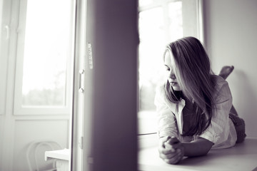 Fototapeta premium beautiful girl lying at home on a window