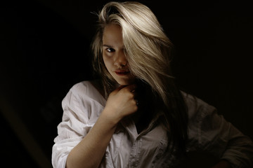 studio portrait of a blond woman on black background