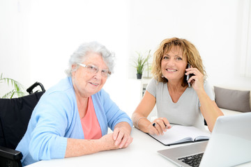 mature woman helping assisted elderly senior female with administrative procedures and paperwork on...