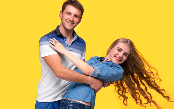 Portrait of a young couple standing against yellow background