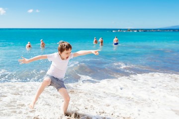 Happy child jumping and playing on the beach