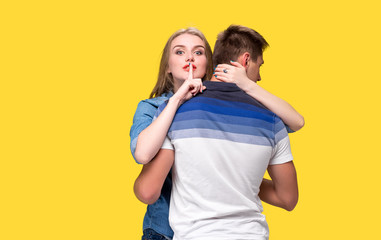 Portrait of a young couple standing against yellow background