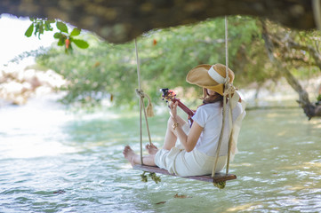 Beautiful woman playing Ukulele by the sea.