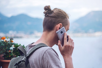 Man traveler with backpack talking on the phone on background of the city.