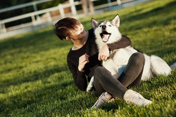 Beautiful young woman playing with funny husky dog outdoors at park 