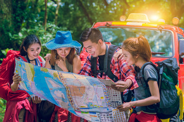 Hiking and Adventure in forest - Asian hikers looking at map. Couple or friends navigating together keep smiling happy during camping travel hike outdoors in forest. Young mixed race woman and man.