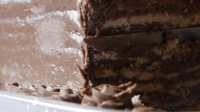 Woman uses knife for chocolate cake close-up 4K 2160p 30fps UltraHD footage - Cutting on pieces multilayered torte with biscuits 3840X2160 UHD video
