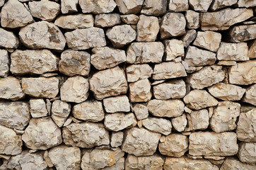 an old stone wall made of loose stone blocks - a natural rock mosaic like pattern