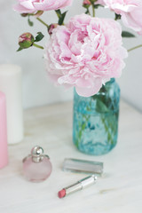 Bouquet of pink peonies in a vase. Bouquet of peonies in a vase, macaroon, cosmetics on the table. Dressing table.