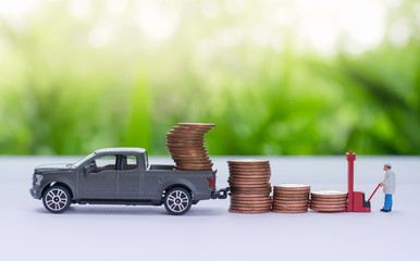 Miniature truck carrying stack of coins, worker loading stack of coins using as a business concept.