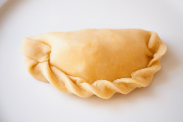 Raw empanadas on white plate ready to get baked