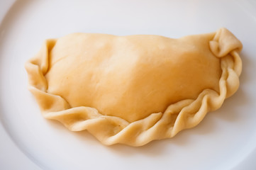 Raw empanadas on white plate ready to get baked
