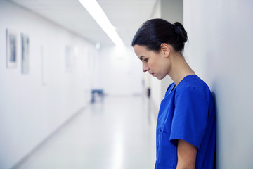 sad female nurse at hospital corridor