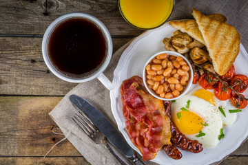 Fototapeta na wymiar Full english breakfast - eggs, bacon, beans, toast, coffee and juice
