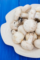 fresh mushrooms in white plate on wooden background
