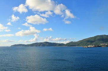 Ocean and mountain landscape with blue sky and white clouds