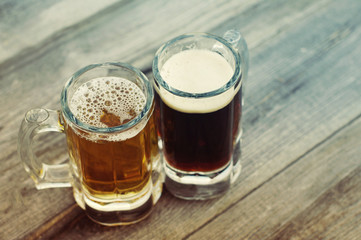 Two glasses of beer on a wooden board. Light and dark beer in glasses
