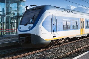 Naklejka premium Pociąg elektryczny jedzie w pobliżu peronu kolejowego