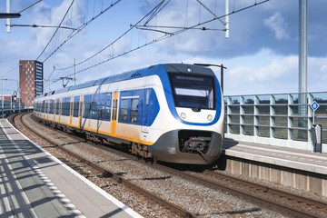 Fototapeta premium Passenger electric train goes near railway platform