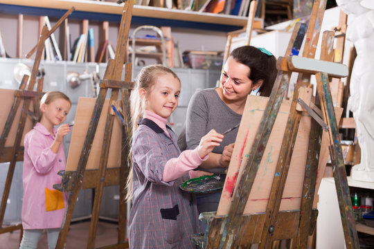 Female teacher assisting student during painting class