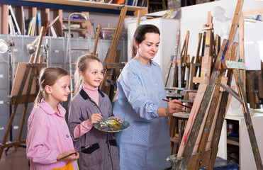 Skillful woman teacher showing her skills during painting class at art studio