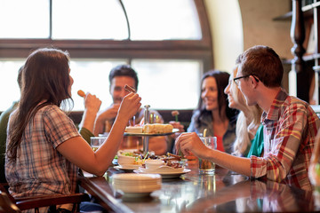 happy friends eating and drinking at bar or pub