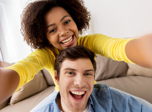 happy multiethnic couple taking selfie at home
