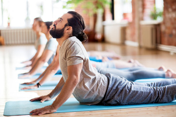 group of people doing yoga cobra pose at studio