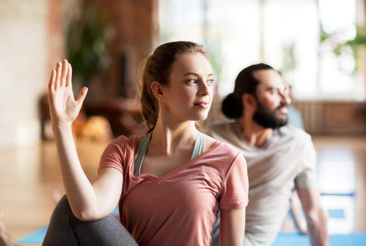 woman with group of people doing yoga at studio
