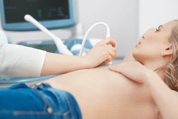 Cropped shot of a woman getting ultrasound scanning examination at the hospital breast cancer...
